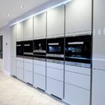 White gloss sleek handless tall larder units housing high-end Miele integrated appliances.