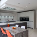 Hacker handless gloss graphite base and island units mixed with light grey gloss wall and tall units featuring stainless steel slimline handles.