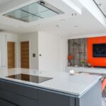 Discrete Miele ceiling mounted extractor hood with matching induction hob on kitchen island, and pop up power socket for easy acess to power any hand held appliance when cooking.