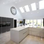 A mixture of light grey gloss and matt graphite handless Hacker kitchen units with matching stianless steel handless trim and plinth with feature micro dot plinth lights.