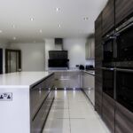 Modern German kitchen fitted with a wall of 4 matching Siemens ovens and compacts.