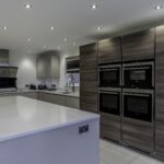 Light bright and earthy warm tones throughout this Hacker handless kitchen help create a welcoming atmosphere with the cool modern look of the appliances and fixtures.